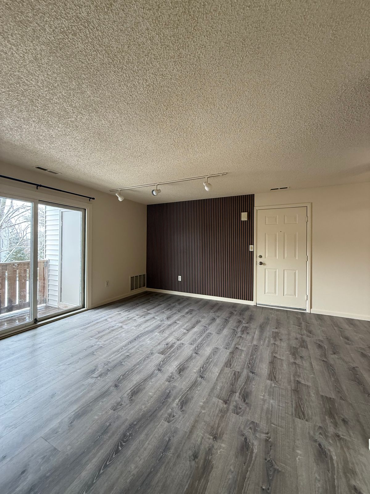 Open living area with LVP flooring and accent wall